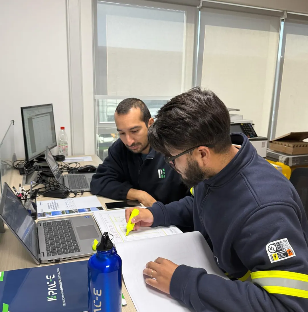 Ingenieros de PAC-E revisando planos de ingeniería en la oficina